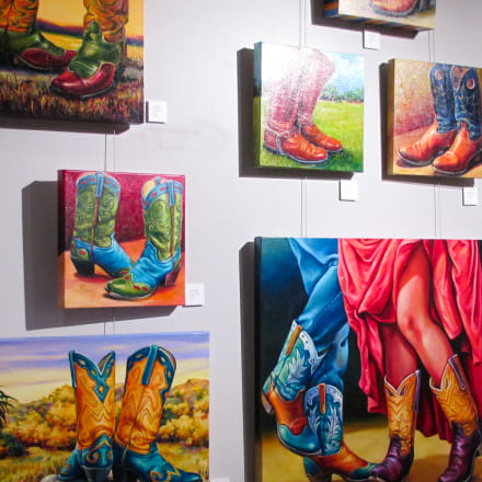 Several canvases of colorful boots paintings displayed on the wall