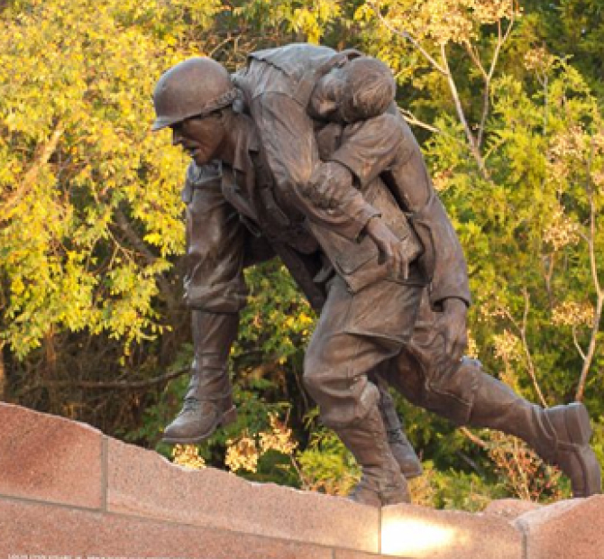 Metal statue of a soldier carrying another soldier on his back