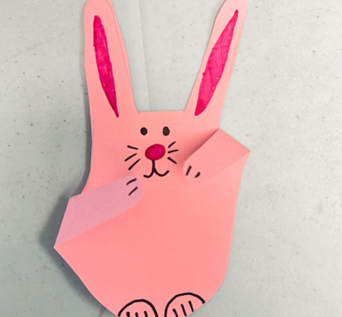 Pink bunny drawn on the cut out shape of a traced hand