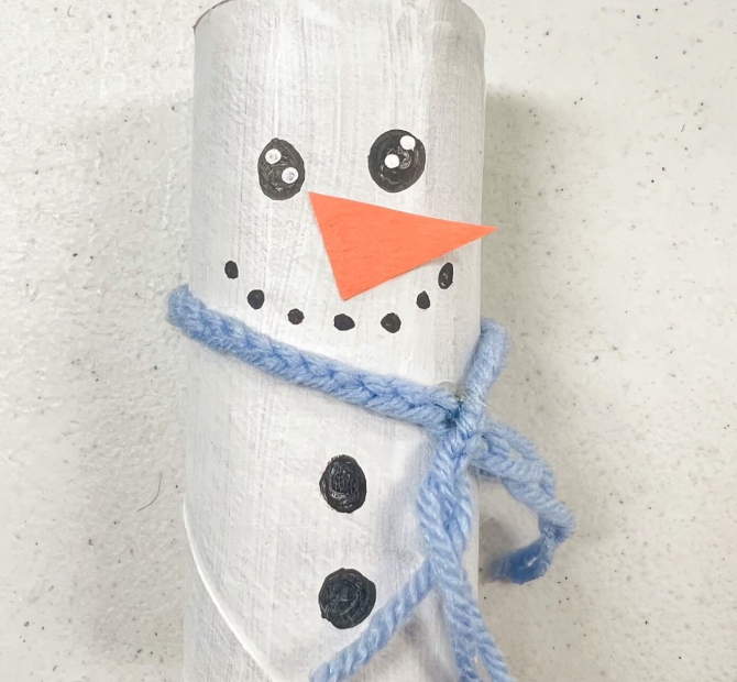 toilet paper roll painted white and decorated with construction paper and yarn to look like a snowman