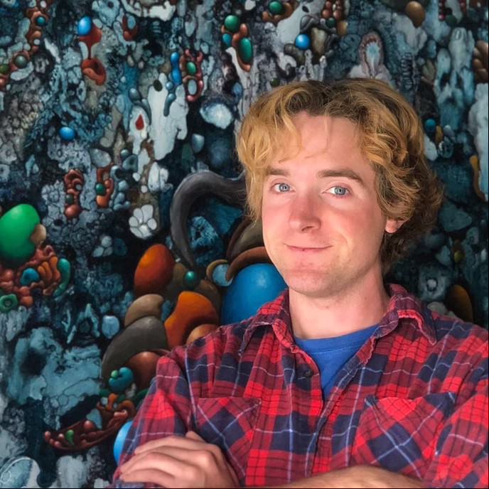 Headshot of Devin Cogger standing in front of an abstract painting