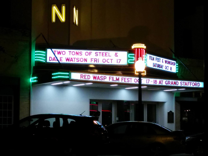 a movie theater lit up at night with neon signs that say 