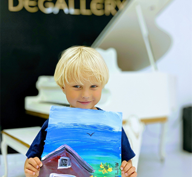 Blonde little boy holding a painting of a barn and sunflowers